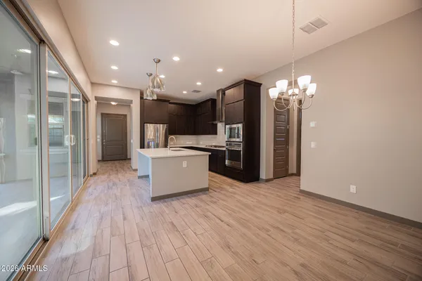 a large kitchen with a refrigerator and a wooden floor