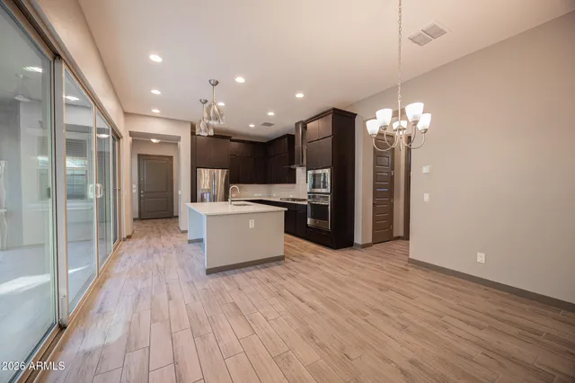 a large kitchen with a refrigerator and a wooden floor