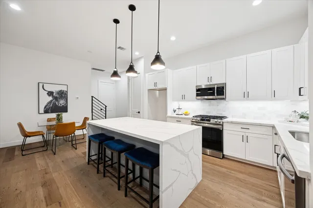 a kitchen with stainless steel appliances kitchen island a table chairs sink and cabinets