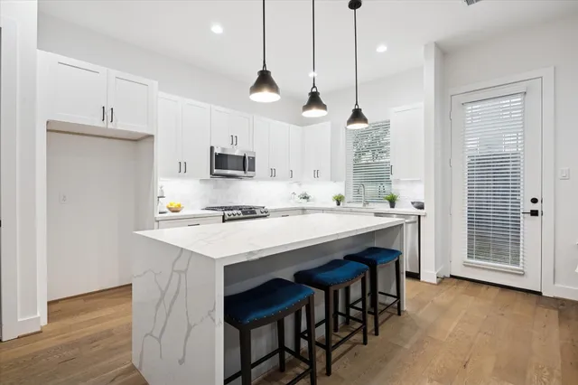 a kitchen with kitchen island a sink a stove a refrigerator and a island with wooden floor