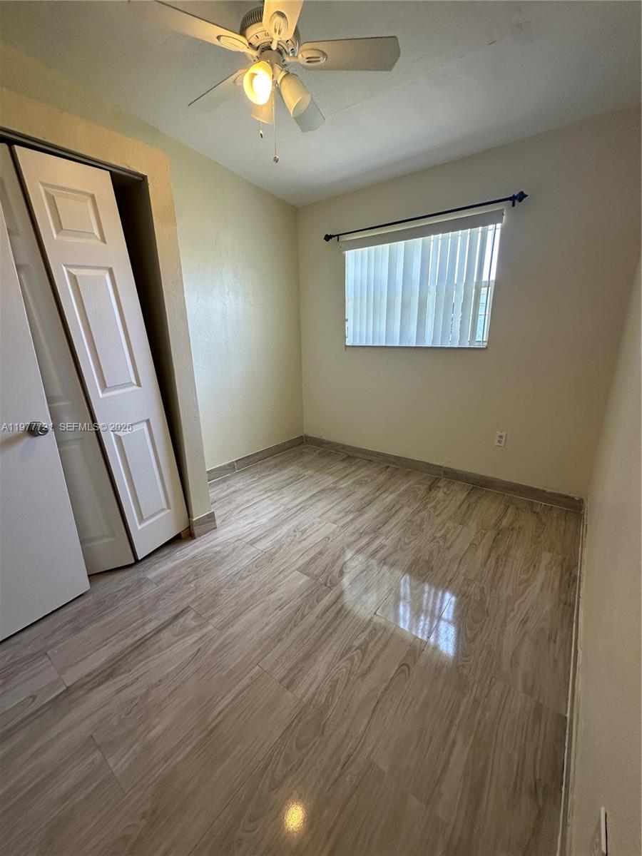 10761 Southwest 221st Street Miami, FL 33170 - Photo 21 of 32 a view of an empty room with wooden floor and a window