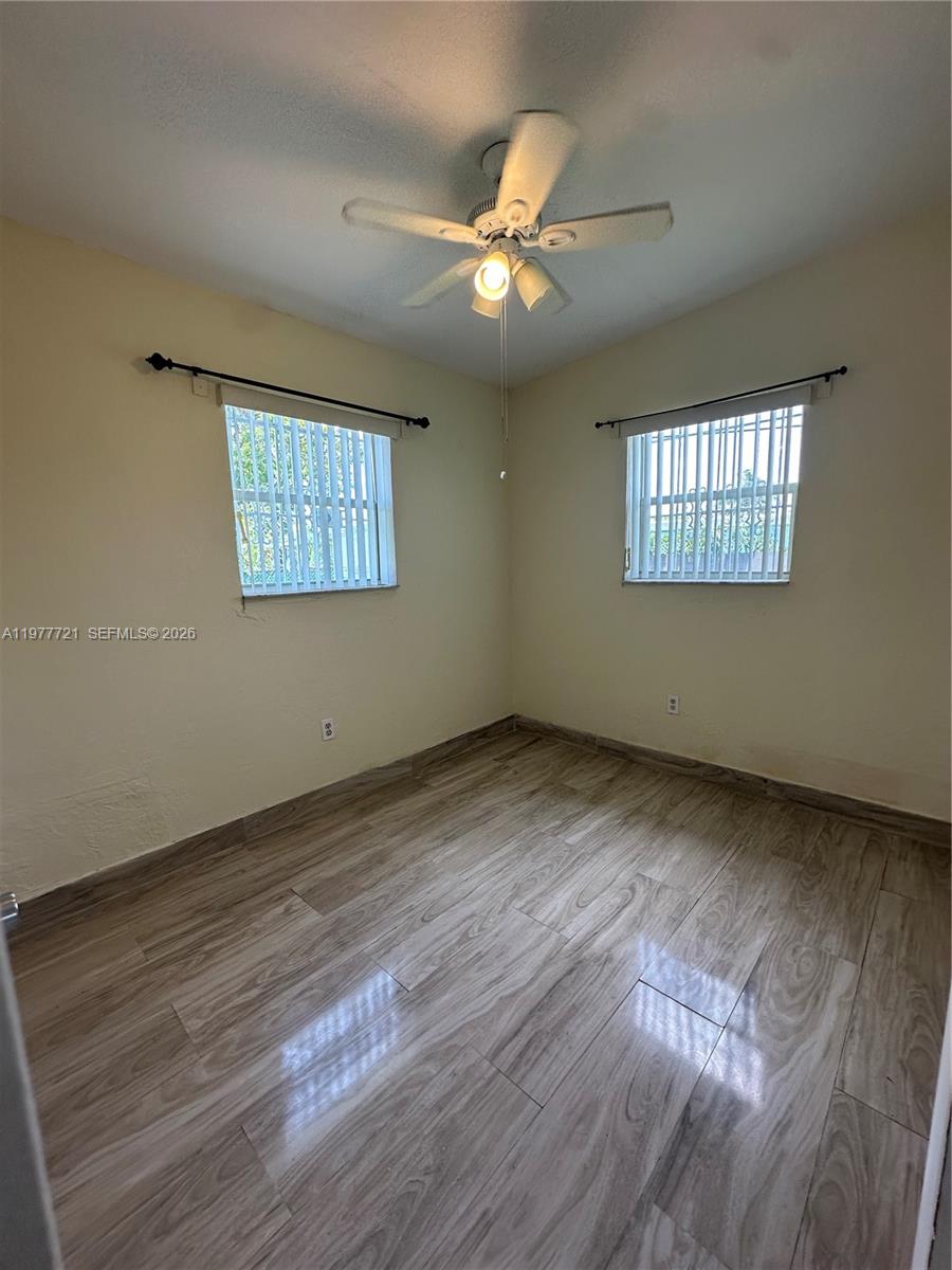 10761 Southwest 221st Street Miami, FL 33170 - Photo 22 of 32 a view of an empty room with a window and wooden floor