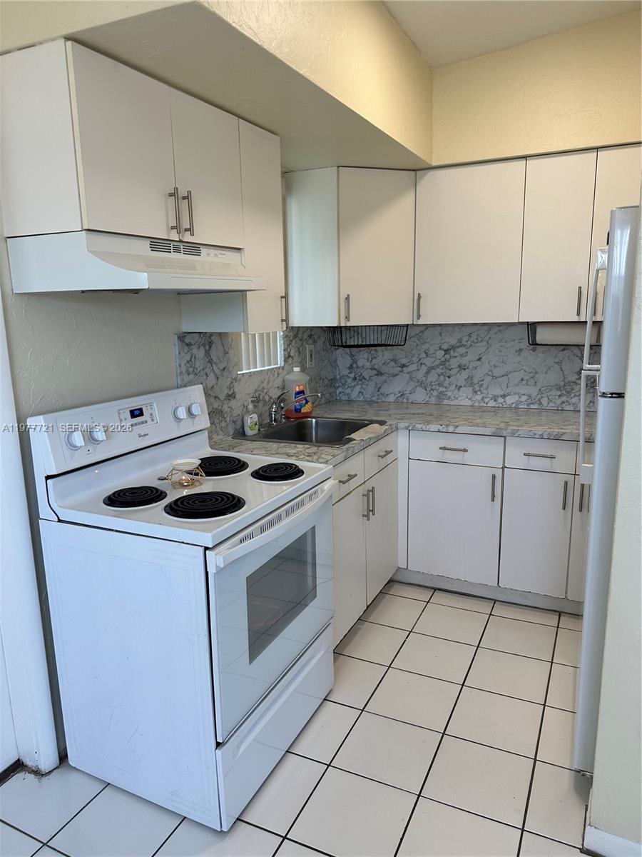 10761 Southwest 221st Street Miami, FL 33170 - Photo 24 of 32 a kitchen with a stove sink and cabinets