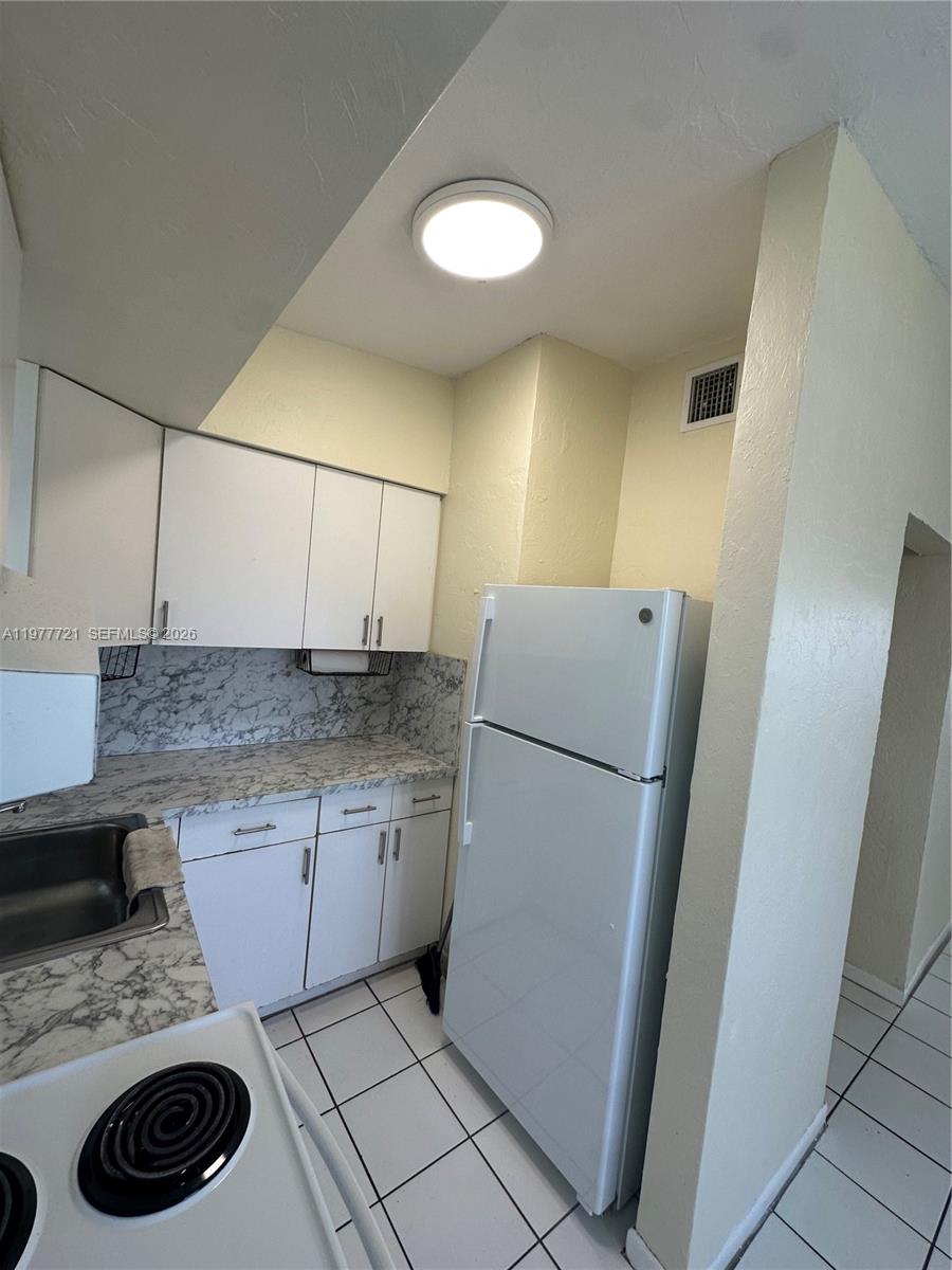 10761 Southwest 221st Street Miami, FL 33170 - Photo 25 of 32 a kitchen with a refrigerator sink stove and cabinets