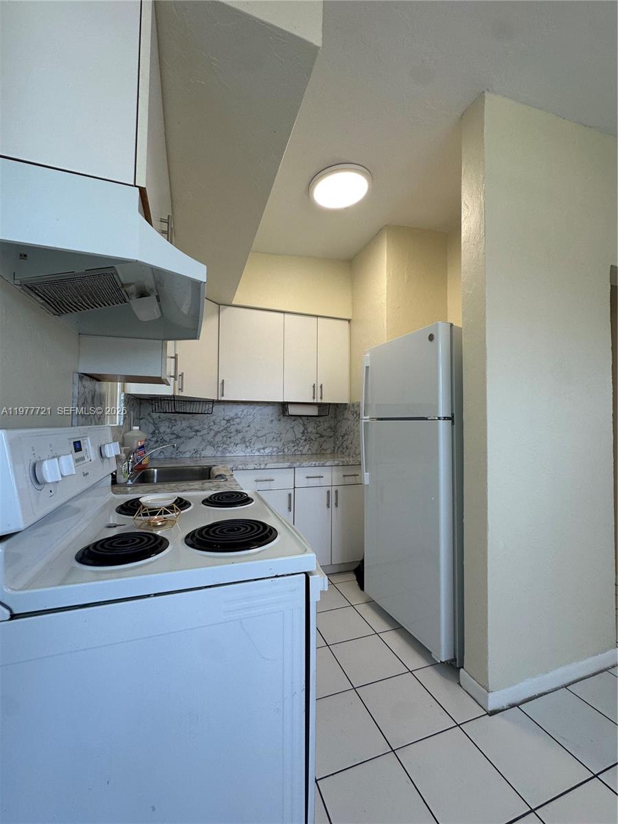 10761 Southwest 221st Street Miami, FL 33170 - Photo 27 of 32 a kitchen with a refrigerator a stove a sink and cabinets