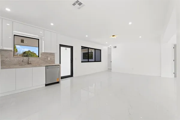 a view of a kitchen with stainless steel appliances a large counter top and sink