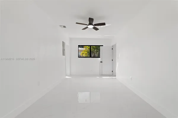 an empty room with windows and fan