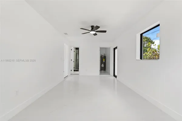an empty room with windows and ceiling fan