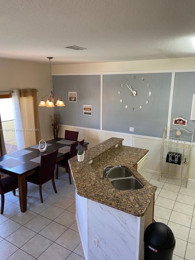 8570 Bay Lilly Loop Kissimmee, FL 34747 - Photo 6 of 36 a kitchen with a granite countertop sink a stove and a wooden floors