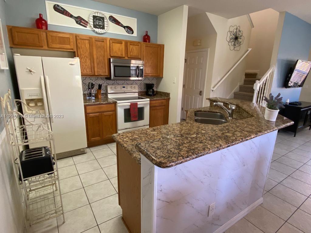 8570 Bay Lilly Loop Kissimmee, FL 34747 - Photo 7 of 36 a kitchen with stainless steel appliances kitchen island granite countertop a refrigerator stove and oven