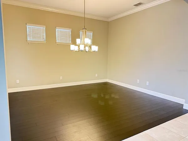 a view of empty room with wooden floor and chandelier