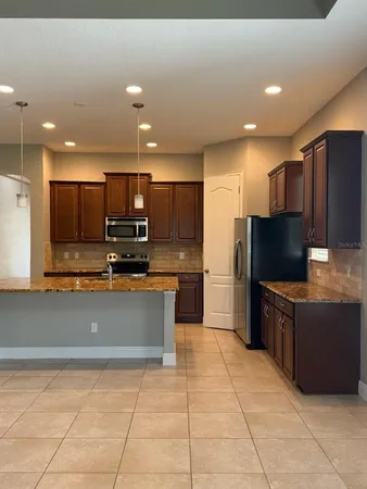 a kitchen with stainless steel appliances kitchen island granite countertop a refrigerator and a stove top oven