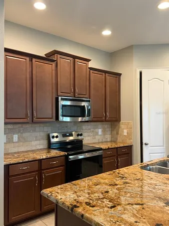 a kitchen with kitchen island granite countertop a sink stainless steel appliances and cabinets