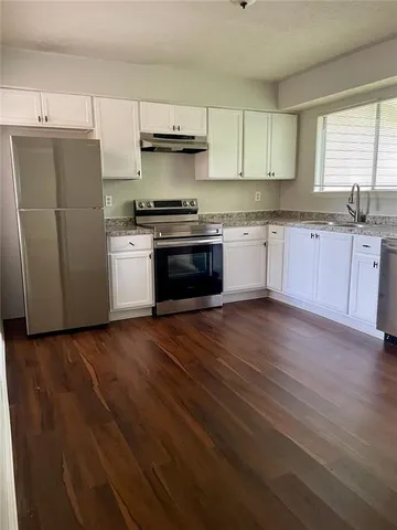 a kitchen with granite countertop white cabinets and a stove top oven