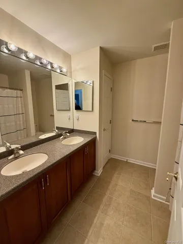 a spacious bathroom with a double vanity sink a mirror and a shower