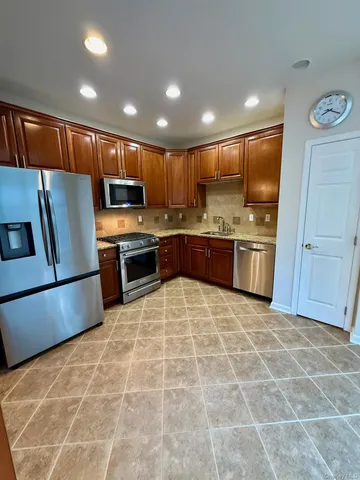 a kitchen with stainless steel appliances granite countertop a stove top oven a sink and a refrigerator