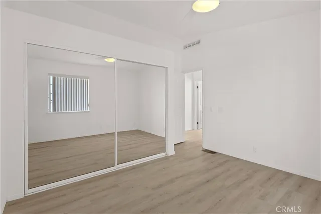 a view of an empty room with wooden floor and window