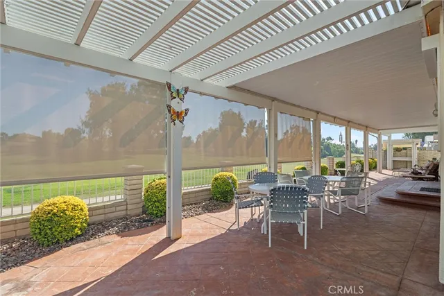 a view of a patio with chairs and floor to ceiling window next to a yard