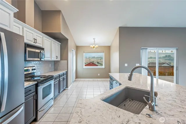a kitchen with stainless steel appliances granite countertop a stove a sink and a microwave