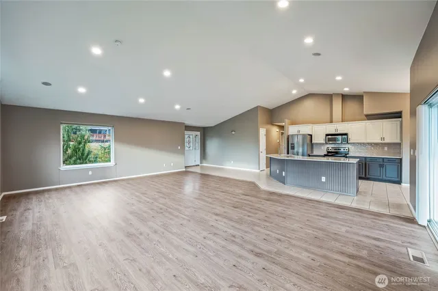 an open kitchen with kitchen island a sink wooden floor and a counter top space