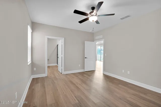 an empty room with wooden floor and a ceiling fan
