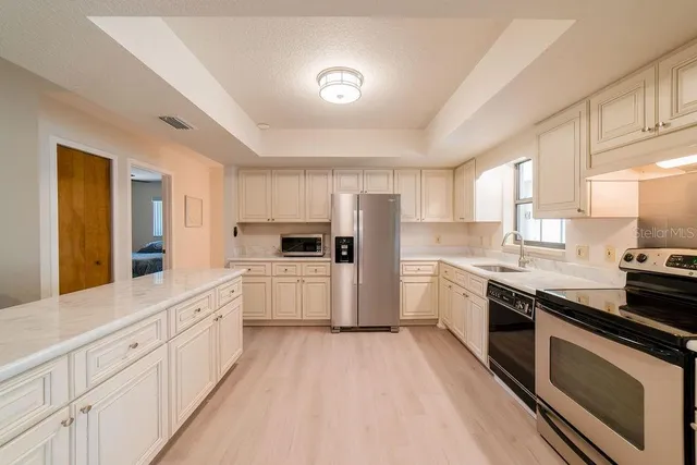 a large kitchen with white cabinets and stainless steel appliances