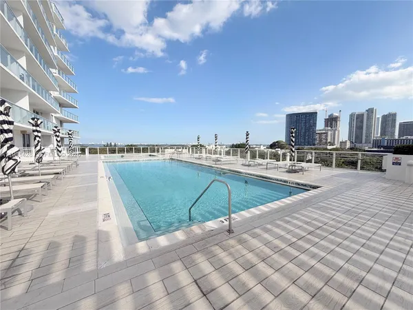 a view of a swimming pool with an outdoor seating and a floor to ceiling window