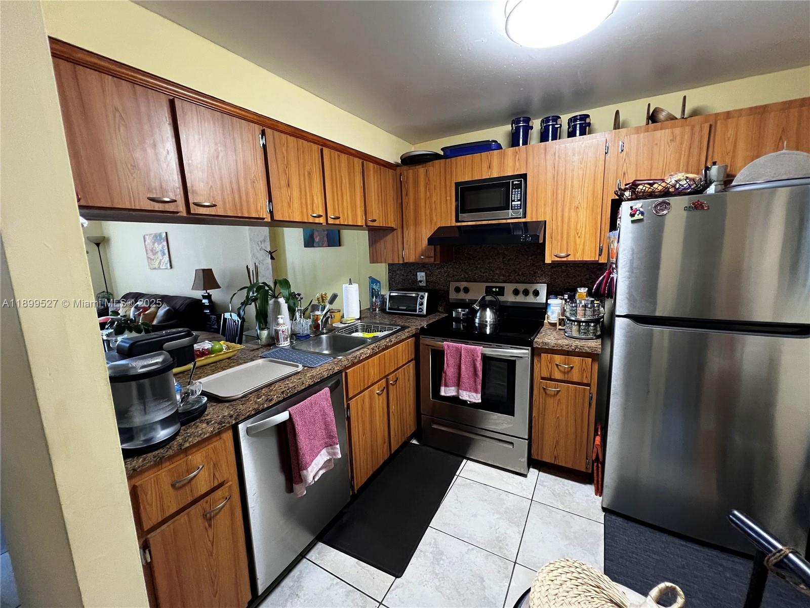14175 Southwest 87th Street, Unit C208 Miami, FL 33183 - Photo 5 of 8 a kitchen with stainless steel appliances granite countertop a refrigerator stove top oven a sink and dishwasher