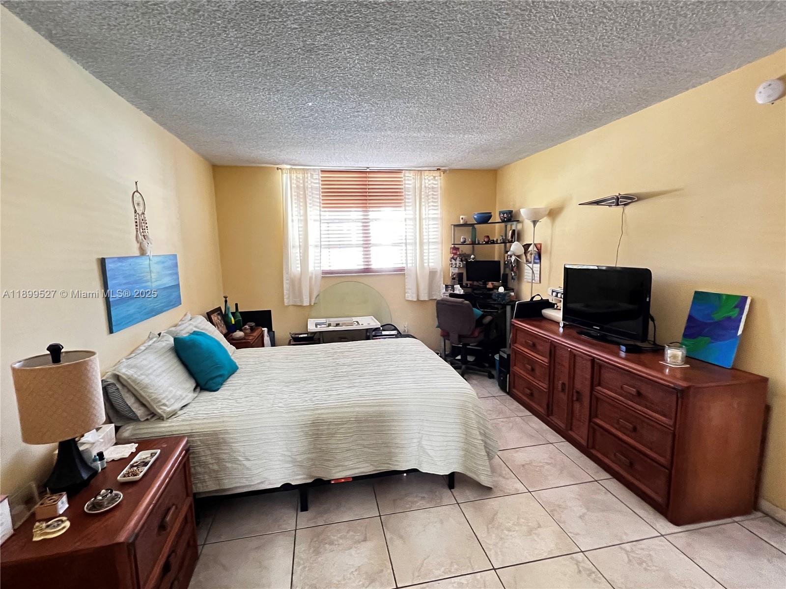 14175 Southwest 87th Street, Unit C208 Miami, FL 33183 - Photo 6 of 8 a bedroom with a bed and flat screen tv