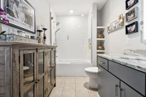 a bathroom with a granite countertop sink a toilet a mirror and shower