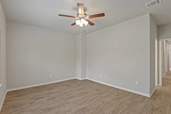 a view of a room with wooden floor and a ceiling fan