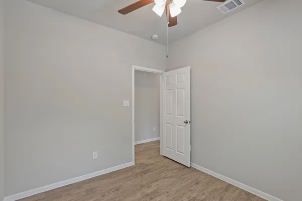 an empty room with a hallway and a chandelier fan