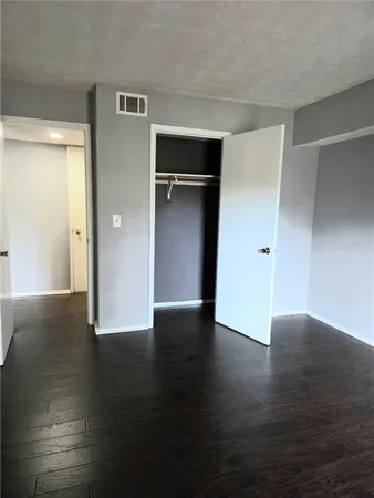 a view of an empty room with wooden floor & closet