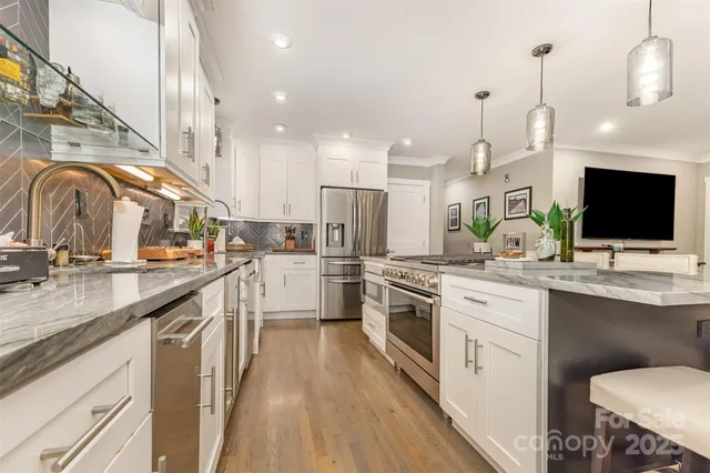 a kitchen with stainless steel appliances a sink dishwasher a stove a microwave oven with white cabinets and wooden floor