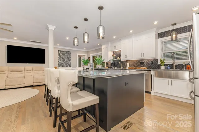 a kitchen with stainless steel appliances kitchen island granite countertop a sink a microwave a dining table and chairs