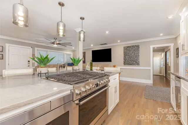 a kitchen with stainless steel appliances kitchen island granite countertop a sink a stove and a wooden floors