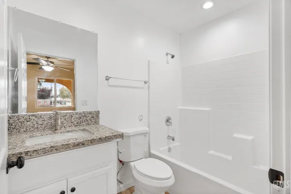a bathroom with a granite countertop sink toilet mirror and bathtub