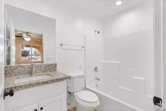 a bathroom with a granite countertop sink toilet mirror and bathtub