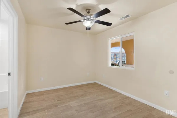 an empty room with ceiling fan and window