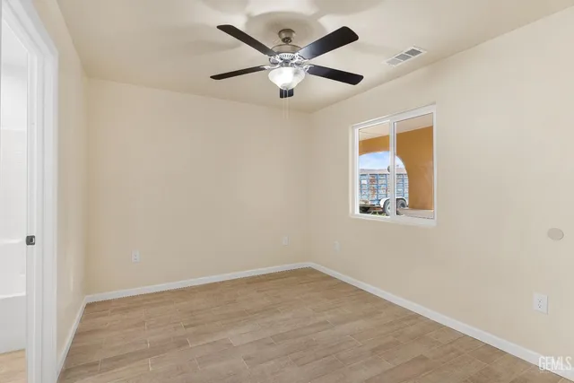 an empty room with ceiling fan and window