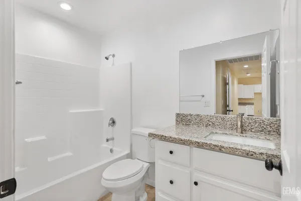 a bathroom with a granite countertop sink a toilet and shower