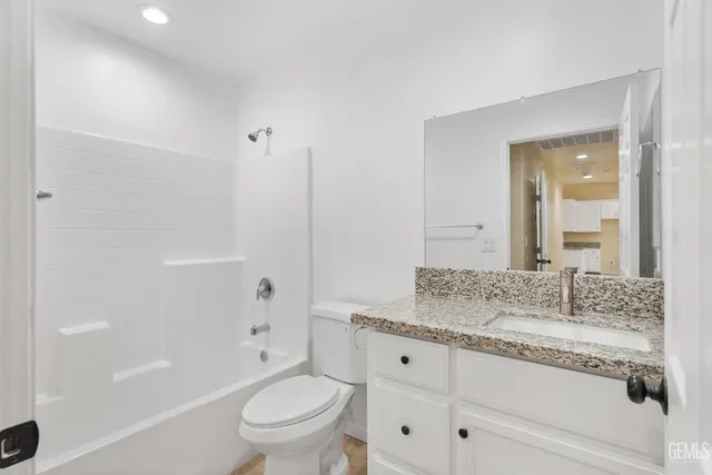 a bathroom with a granite countertop sink a toilet and shower