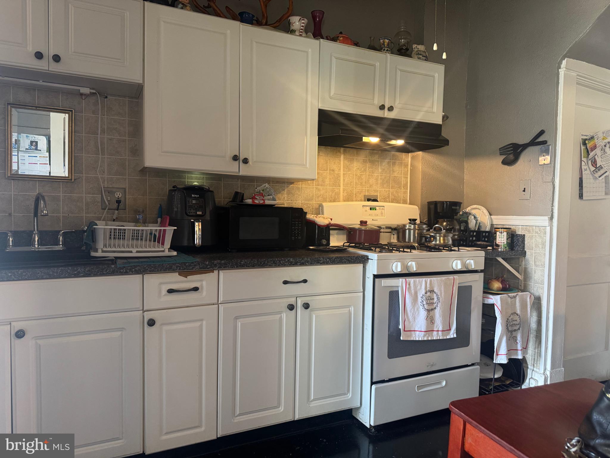 2214 North Monroe Street Baltimore, MD 21217 - Photo 6 of 19 a kitchen with granite countertop white cabinets and black appliances