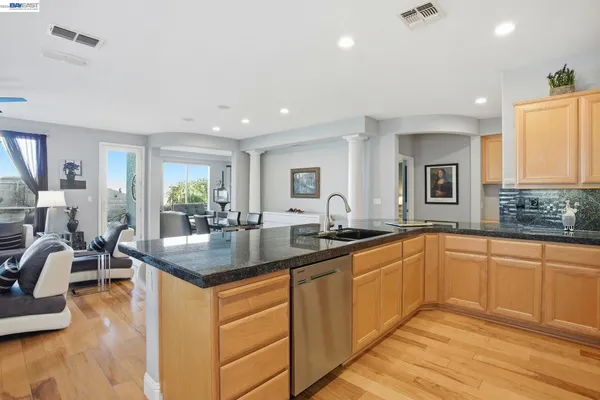 a kitchen with granite countertop a sink and white cabinets with wooden floor