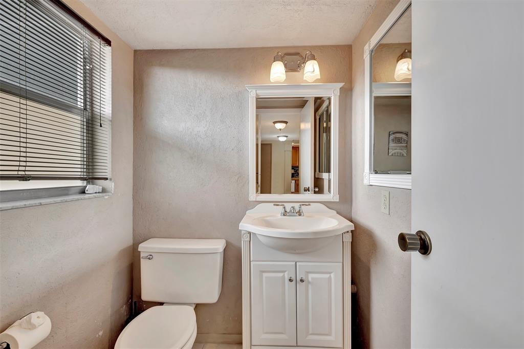 8380 Sands Point Boulevard, Unit J306 Tamarac, FL 33321 - Photo 25 of 33 a bathroom with a toilet a sink and mirror