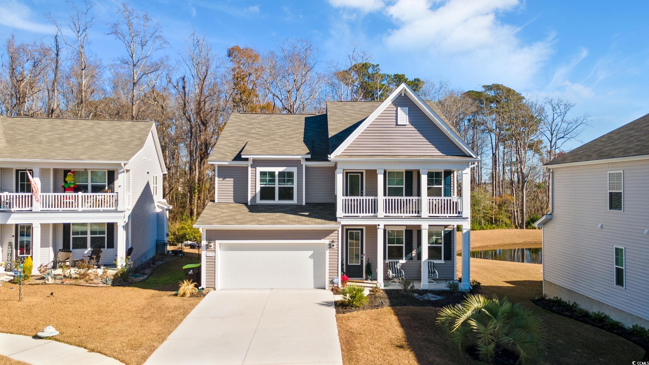 Traditional home featuring driveway, roof with shingles, a porch, and an attached garage