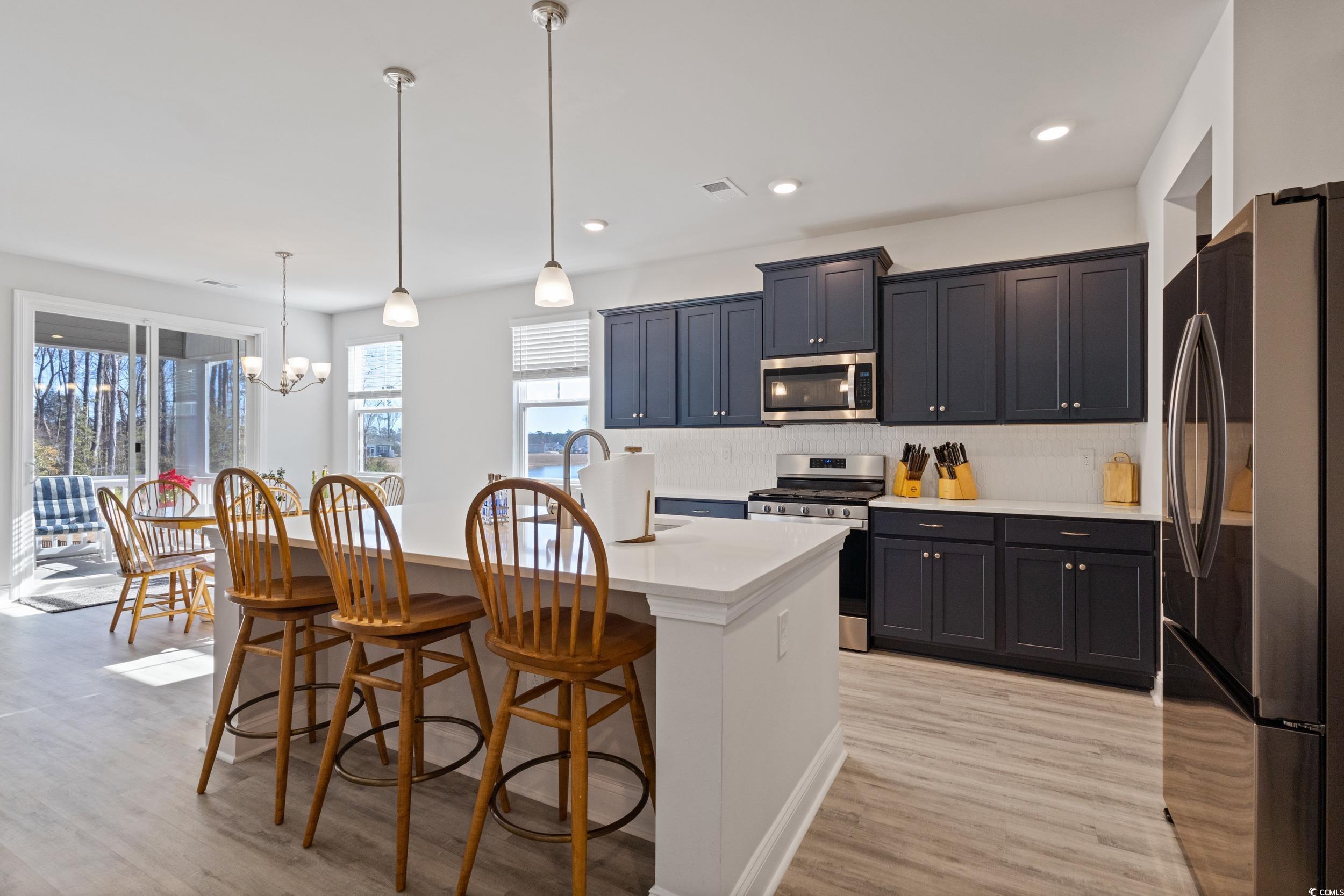 4070 Rutherford Court Little River, SC 29566 - Photo 11 of 40 Kitchen with stainless steel appliances, a breakfast bar area, pendant lighting, light wood-style floors, and a center island with sink