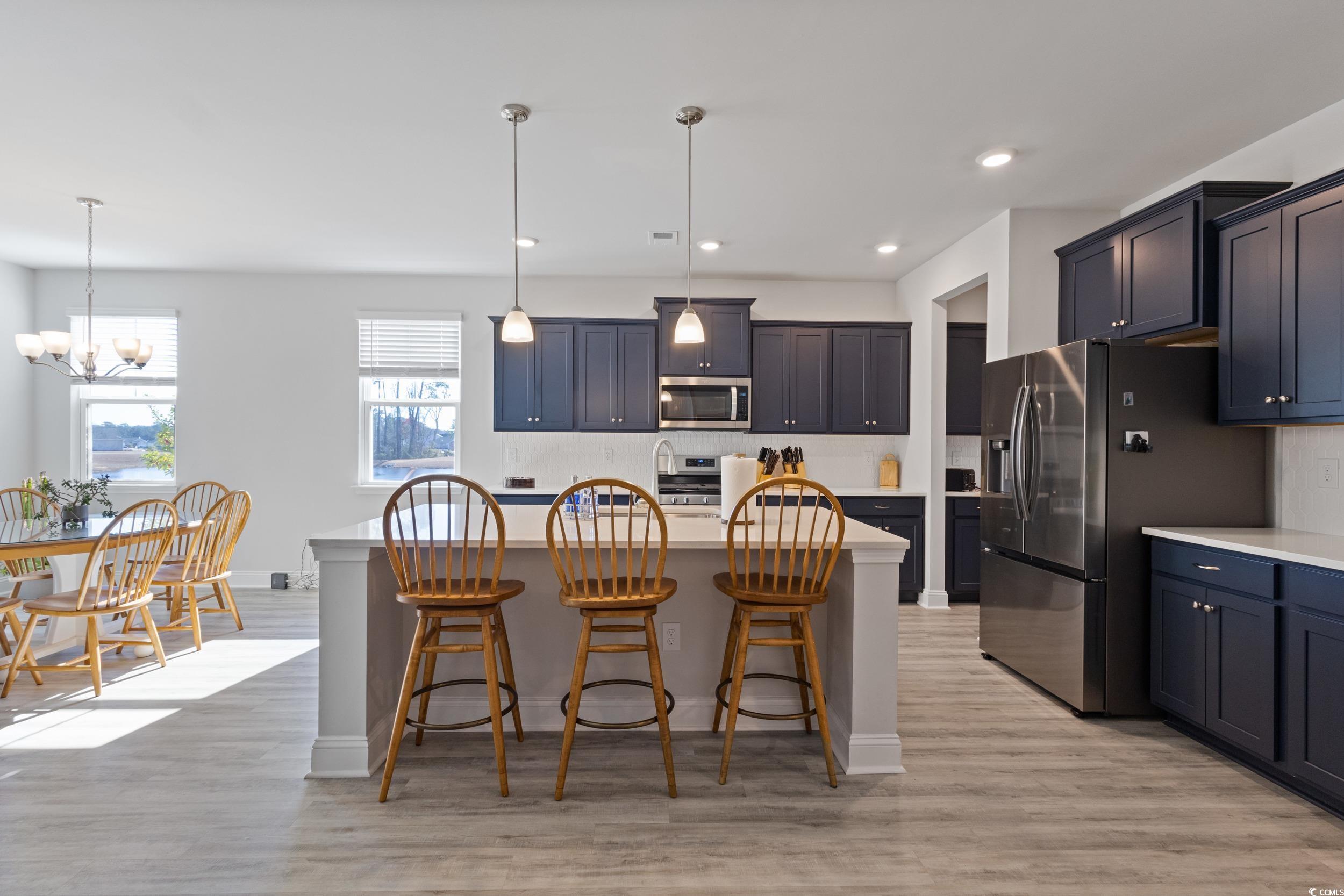 4070 Rutherford Court Little River, SC 29566 - Photo 13 of 40 Kitchen with decorative light fixtures, a kitchen breakfast bar, stainless steel appliances, a kitchen island, and light wood finished floors