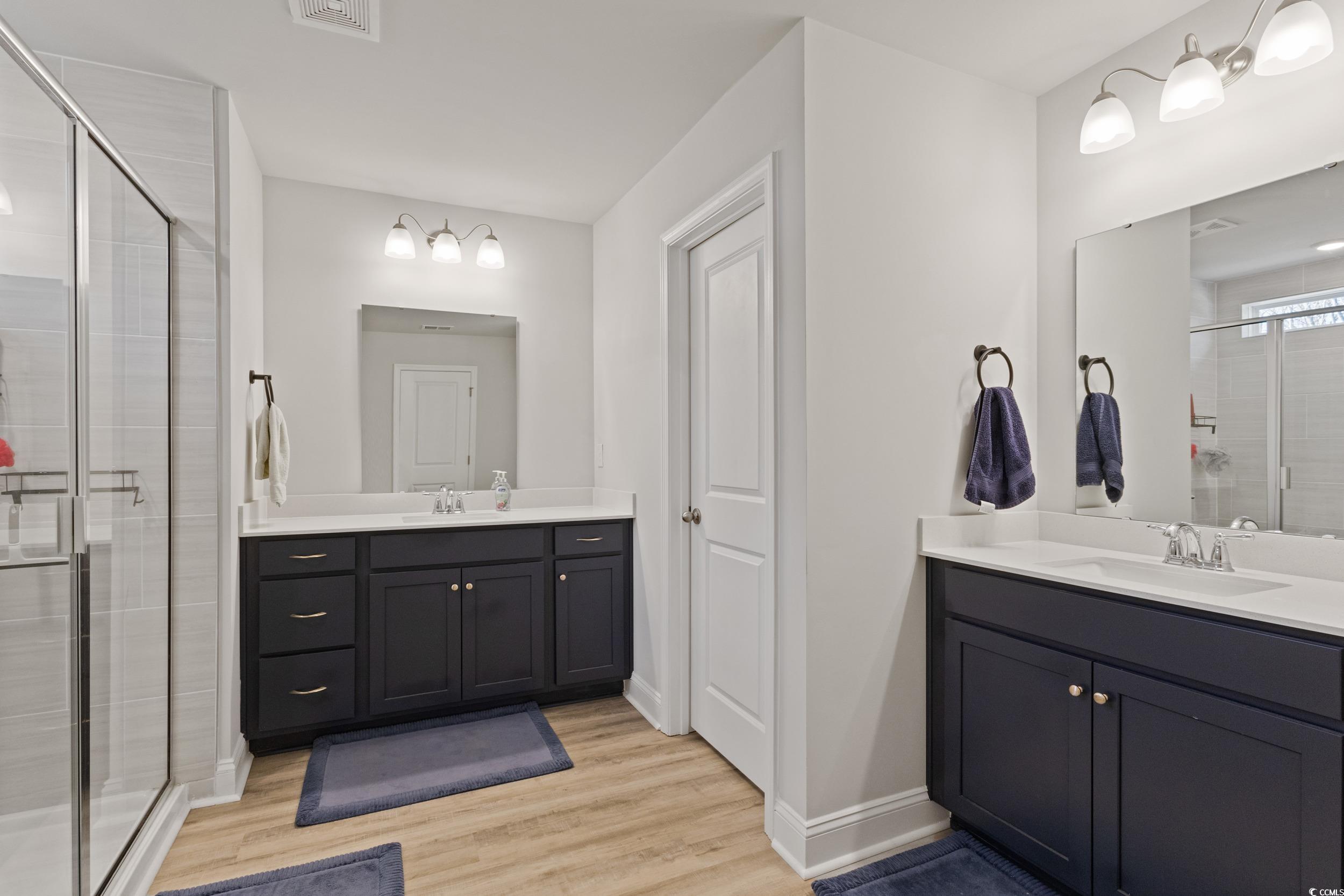4070 Rutherford Court Little River, SC 29566 - Photo 22 of 40 Full bathroom with a stall shower, two vanities, and light wood-style floors