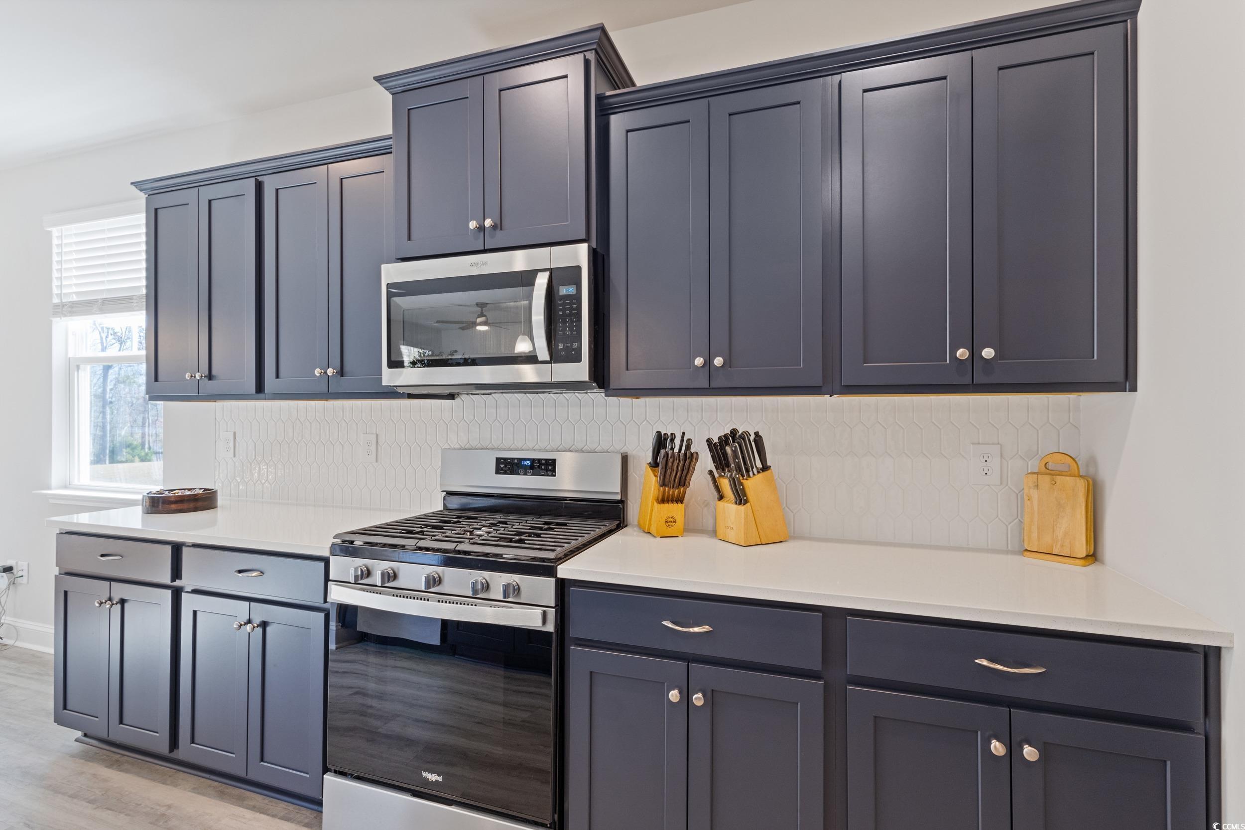 4070 Rutherford Court Little River, SC 29566 - Photo 9 of 40 Kitchen featuring stainless steel appliances, light stone countertops, backsplash, and light wood-type flooring